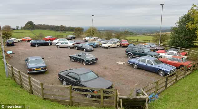 A long shot, but anyone know what happened to this SEC?  - Page 1 - Mercedes - PistonHeads - The image shows a parking lot, likely for a car dealership, filled with a diverse array of cars. There is a variety of makes and models, including both modern and vintage cars. Some of the cars are parked meticulously in rows, while others appear randomly scattered throughout the lot. The lot itself is fenced and situated in a countryside setting, as indicated by the open fields and likely trees in the background. The sky is overcast, suggesting a cool or cloudy day.