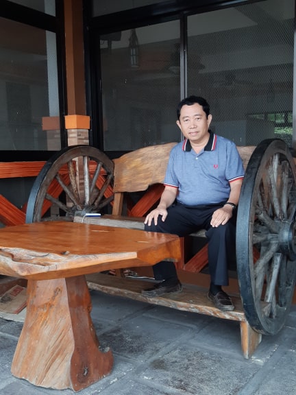 A man sitting on a wooden bench with a laptop