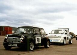 Pistonheads Canterbury Cosworth Mini - The image features two vintage cars parked side by side. The car on the left has the registration number "78" on the side, while the car on the right has a white and blue registration plate, which appears to be from a region or country where such color palettes are common, such as Germany. The vehicles are parked on what seems to be a runway or a dirt road, as indicated by the open space and the overcast sky in the background. The cars have the classic rounded fronts typical of older vehicle models. No people are visible, and the focus of the image is on the cars and their immediate surroundings, suggesting a sense of stillness and nostalgia.