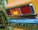 A suitcase sitting on the floor next to a window - Pistonheads - The image shows a close-up view of the back of a yellow car, focusing on the license plate area. The primary element in the shot is a back taillight, which is in the process of changing colors, indicating a signal to turn or stop. To the left of the image, there is a blurred green plant partially visible. The background of the image is yellow, matching the color of the car, providing a soft transition to the vehicle's back. There's a sense of motion and vibrancy in the photo, potentially capturing the moment before the car begins to turn or stop.