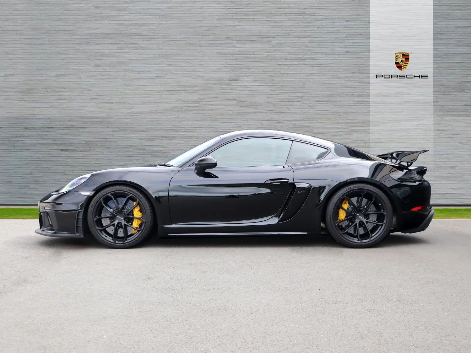 GT4 RS breaks cover then... - Page 149 - Boxster/Cayman - PistonHeads UK - The image displays a black, high-performance sports car parked on a paved surface. The vehicle is positioned at an angle that showcases its design and features. It appears to be equipped with performance upgrades such as a larger spoiler and side skirts, which suggest modifications for enhanced aerodynamics and possibly additional horsepower. The car is fitted with low-profile wheels and high-performance tires, typical of sports cars. There's a badge in the lower left corner that resembles a Porsche logo, indicating the brand of the vehicle. The image has an overlay graphic of a keychain or lock, which might be a watermark or part of the photography technique used to capture this photo.