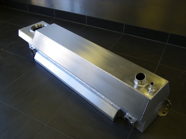 A toaster oven sitting on top of a counter - Pistonheads - The image features a sleek, metallic object that resembles a vibrating plate or a speaker, laid down on its side. The object gleams in the light, displaying a silver-colored, possibly brushed or polished metal surface. It is constructed with straight lines and angles, suggesting a modern and minimalist design. The uniquely elongated shape and the presence of what appears to be a hole or a flange, possibly for mounting or fitting into another device, further enhance its specialized, industrial appearance. The background, which consists of a tiled floor and a black wall, contrasts with the metallic object, accentuating its gleaming surface.