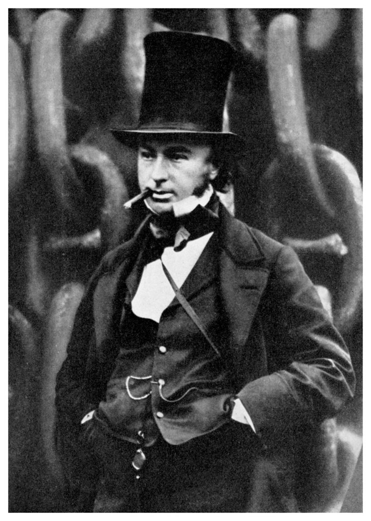 Tell us something really trivial about your life (Vol 29) - Page 500 - The Lounge - PistonHeads - The image is a black and white portrait of a man who appears to be of middle age. He is wearing a top hat and a lavish costume that includes a high-collared shirt, a bow tie, and a coat with a belt at the waist. The man is holding a cane in his right hand and is holding a cravat in his left. The backdrop consists of a repeated pattern of curved line shapes. The style of the image suggests it may be from the late 19th or early 20th century, indicated by the fashion and the nature of the portrait.