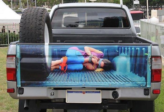 Badly modified cars thread - Page 281 - General Gassing - PistonHeads - The image captures a scene where a picture of a person is cleverly placed on the back bumper of a truck. The person in the photo is facing a different direction than the truck, creating a captivating optical illusion. The truck is parked outdoors, and a tent can be seen in the background, possibly suggesting an event or gathering. The juxtaposition of the static truck with the dynamic positioning of the person in the image creates a thought-provoking visual. The creative use of the truck's tailgate to display this picture adds a playful and surprising element to the scene.