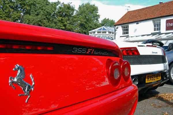 A red and white bus parked in front of a building - Pistonheads - The image showcases a close-up view of the back of a vibrant red Ferrari with a silver emblem, parked in a lot. The car has robust tail lights, and the words "365 FIERLINDA" are visible on the lower left part of the tailgate, indicating the model of the vehicle. The car exhibits a sleek design with a spoiler, and the sky serves as a backdrop in the scene.