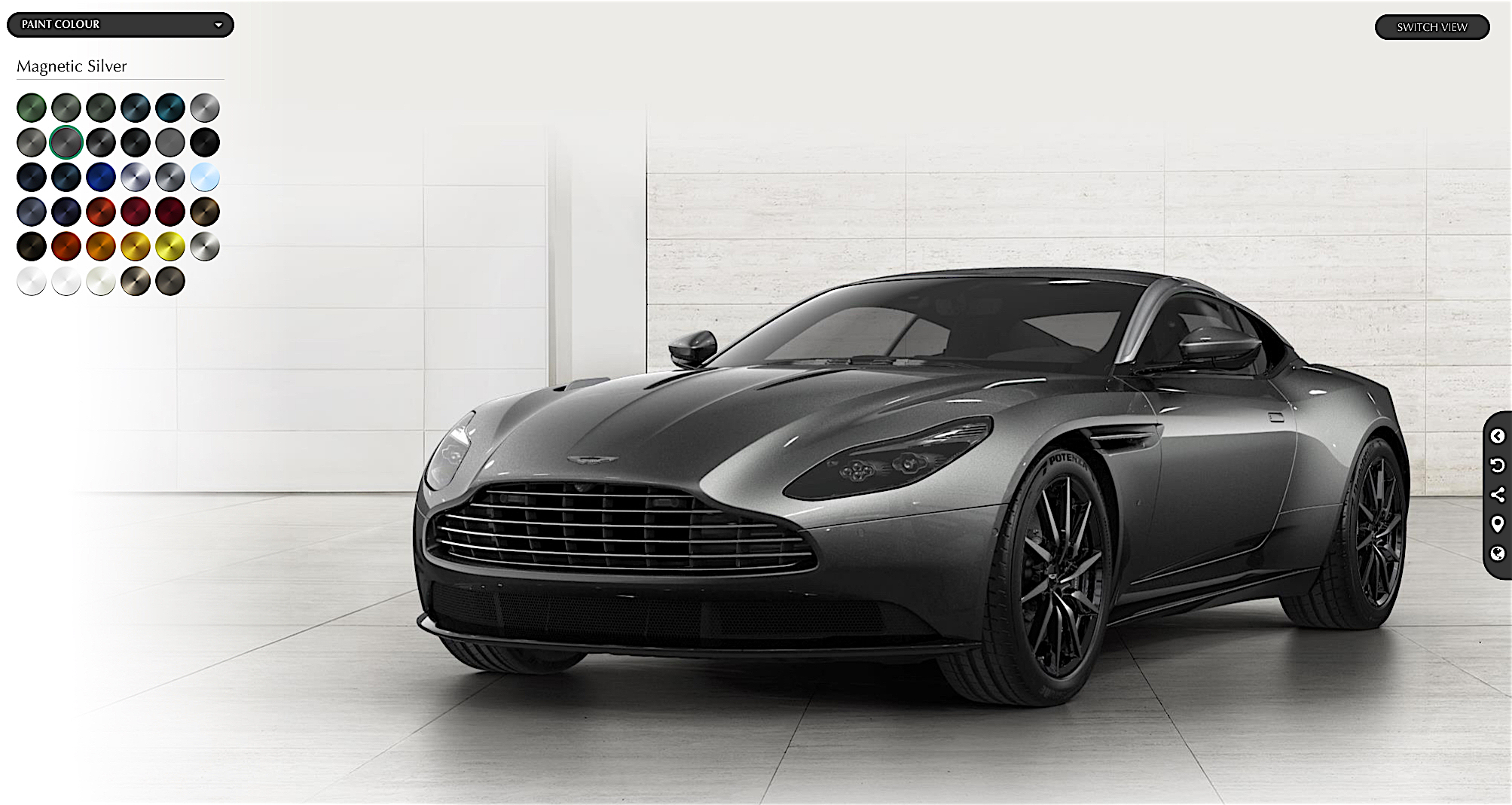 These pictures made me like the DB11 - Page 1 - Aston Martin - PistonHeads - The image displays a sleek, contemporary car positioned at an angle to showcase its design. The car appears to be a two-door with black wheels and a glossy finish, giving it a modern and luxurious aesthetic. The wheels are detailed, suggesting performance and style. The background is minimalistic with a repeated pattern that provides depth, enhancing the prominence of the car within the image. There are no visible texts or logos that indicate the brand or model of the car.