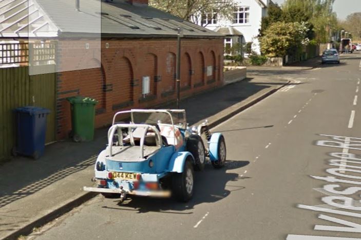 Spotted Ordinary Abandoned Vehicles - Page 49 - General Gassing - PistonHeads - The image shows a blue and white vehicle on a city street with a sidewalk adjacent and a house across the road. The vehicle appears to be a light blue one-wheeled carriage or a similar type of transportation, with seats for passengers and a buggy-like structure. There is an open back and a covered top, suggesting it might be a tourist vehicle on a sightseeing tour.