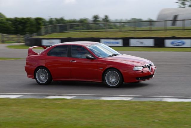 A red car is parked on the side of the road