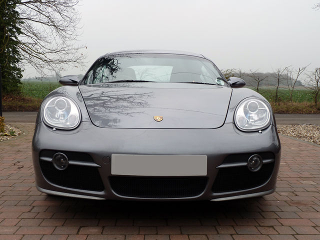 Dareen wanted pictures.... - Page 1 - East Anglia - PistonHeads - The image shows a gray Porsche 911 parked on a brick pavement. The car is facing towards the left side of the image. It's equipped with large, sleek headlights and a distinctive emblem on the hood. Around the car, there are bare trees and a clear sky, suggesting the photo was taken on a cloudless day.