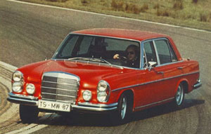 Pistonheads Plans Jay Leno Slspowered Sel - The image captures a vibrant scene on a race track. A red Mercedes 220 car, wearing the number "T5-MW97" and "87" on its licenses, is speeding along a curved track with race tires. The car's sleek lines and Monte Carlo style add to its racing aesthetics, and the man at the wheel appears focused and ready to take a tight turn. The backdrop of the track fades into a light green, providing a striking contrast to the red of the car.