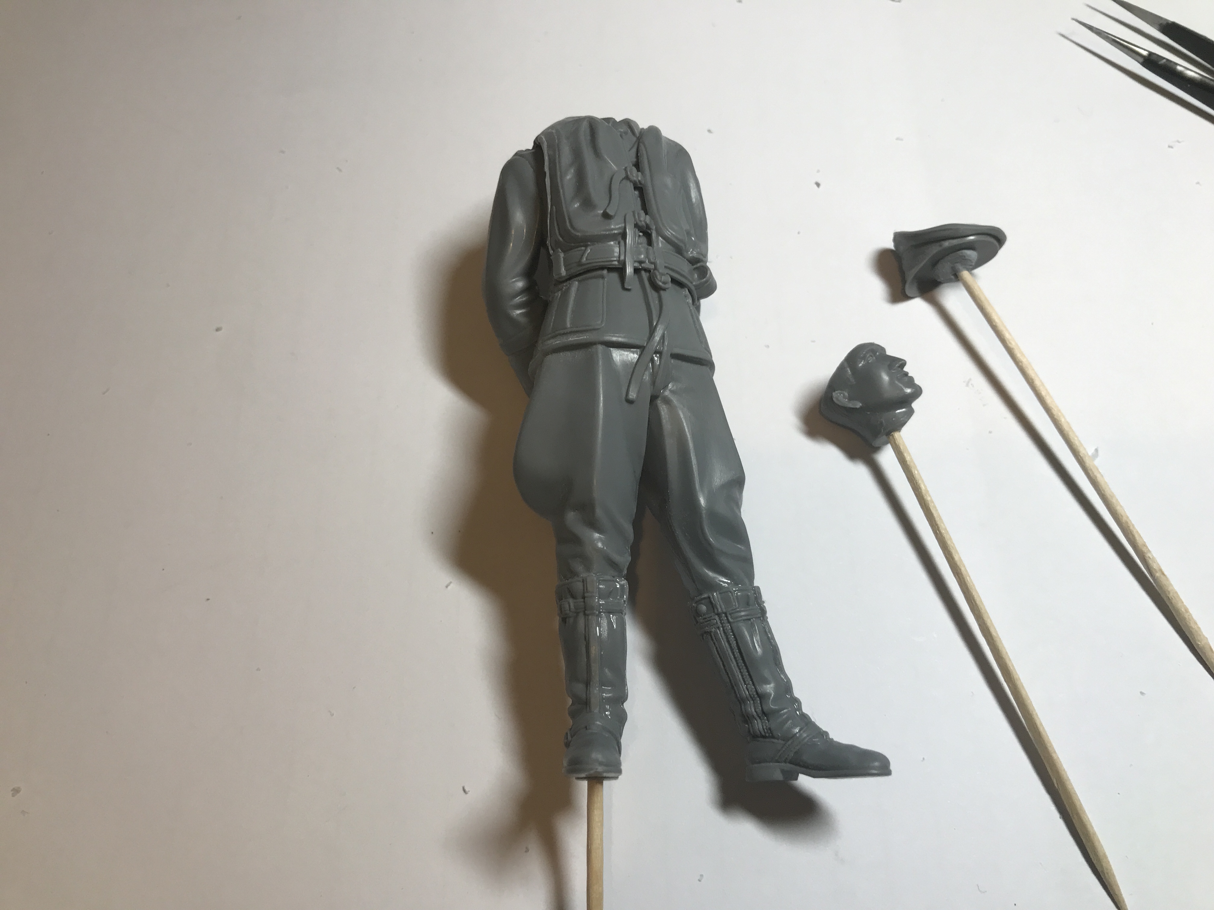 The thread where we can talk about painting figures. - Page 4 - Scale Models - PistonHeads - The image depicts a realistic toy soldier figurine. This figure appears to be in the process of assembly or disassembly, as indicated by several small parts scattered on the table next to it. A couple of toothpicks are also present near the figurine, possibly used for alignment during assembly. In the background, there is a hint of other items that could be related to this toy soldier hobby. The overall setting suggests a space dedicated to model building or collecting.