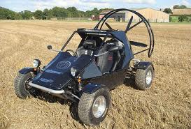 need an off roader - Page 1 - Off Road - PistonHeads - The image features a black all-terrain vehicle (ATV) resting on a field of golden wheat. The ATV is positioned slightly to the left and has a large, circular traction wheel in the foreground. It appears to be a well-built, two-seater utility vehicle, with a distinctive off-road design. The background displays a clear sky, indicating good weather conditions. There is no visible text or distinctive branding on the vehicle.