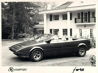 Damn banger racers - Page 2 - General Gassing - PistonHeads - The image is a vintage black and white photograph of a black-and-silver sports car parked in front of a two-story white house with black shutters and a balcony. The car appears to be a mid-1970s model, possibly an Audi or a Porsche, and the setting implies a calm, suburban atmosphere. The automobile has white-walled tires and a convertible roof, which suggests a sense of luxury. The text "Rappaport" and "FORTS" is visible at the bottom of the image, possibly indicating the car owner's name or the name of the company associated with the vehicle. The overall style and features of the car suggest it could be a collector's item or a car of significant historical value.