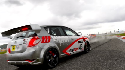 A car is parked on the side of the road - Pistonheads - The image shows a grey car with a prominent rear wing, giving it a sporty appearance. The car is on a race track, as indicated by the red and white striped corners, a common feature at racing circuits to mark the boundaries of the track. The car is identified with the number 43, and there is text on the back of the car that reads "TECH," which likely refers to the brand or team associated with the car. The weather in the image is overcast, with gloomy clouds filling the sky.