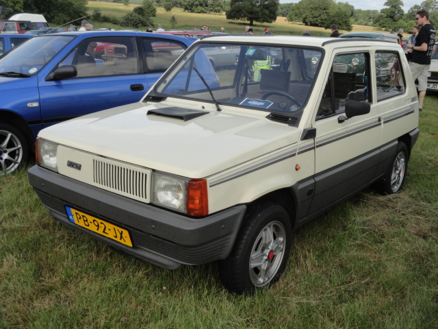 RE: Festival of the Unexceptional | PH Gallery - Page 7 - General Gassing - PistonHeads - The image shows an old-fashioned, compact car parked outdoors. It's a two-door vehicle with a distinctive design, including a curved front bumper and what appears to be a sunroof. The car is painted in a cream or light tan color. A blue license plate is visible on the back of the car. In the background, there are other vehicles and people, suggesting that this photo might have been taken at an outdoor event such as a car show or exhibition.