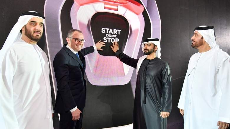 World largest show room in Dubai - Page 1 - Motoring News - PistonHeads - The image captures four men standing side by side, dressed in traditional Saudi attire. They appear to be in a ceremonial or promotional context, as suggested by the backdrop featuring a logo or display with text, one of which reads "START". The men are posing for the photograph with confident smiles, and the ambiance suggests a formal event or announcement.