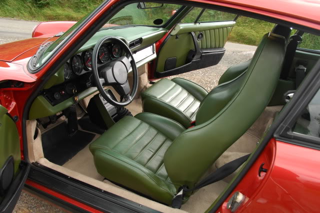 The "Crap colour combo's" thread - Page 2 - General Gassing - PistonHeads - This image shows the interior of an aluminum vintage car, dominated by a vibrant combination of green and red leather and aluminum panels. The car features a large, round steering wheel with various gauges, worn leather seats, and a unique door hinge. The dashboard has various gauges and controls, and the overall ambiance of the car's interior suggests a mix of vintage and luxury elements.