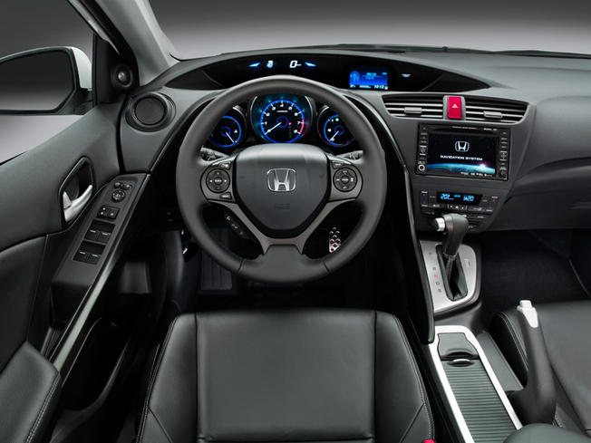 Next Generation Civic - Page 1 - Honda - PistonHeads - The image shows the interior of a car, specifically focusing on the driver's side. The steering wheel is positioned on the right side of the vehicle, and there is a large infotainment screen displaying various icons and indicators, suggesting a multimedia system. Below the screen are buttons and dials, which are typically used for managing music, making phone calls, and adjusting vehicle settings. The car's interior is black, with the driver's seat positioned in an invasive, angled way that is often seen in automobiles with large steering wheels and fully digital instrument clusters. The vehicle appears to be a luxury car, although the make is not visible.