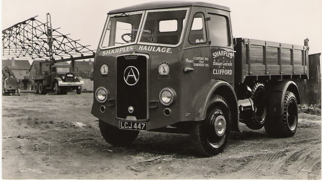 Sharples of Clifford ,livery question - Page 1 - Commercial Break - PistonHeads - The image is a black and white photograph featuring an antique SARPLES B&W HAULAGE truck. The truck is parked on a dirt road with its bed extended upwards, and the label below it reads "CLIFFORD". The truck also has a large "A" symbol on the front. Behind the truck, there's another vehicle, although it's not fully visible; it appears to be a piece of heavy machinery or a large truck cab. The scene can also be inferred to be an industrial or construction site due to the vehicles and the partially visible equipment. The image falls under the category of transportation or industrial history.