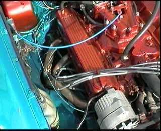 sebring v8 conversion - Page 1 - MG - PistonHeads - The image shows the engine compartment of a vehicle, providing a view from the bottom side. You can see the large, complex structure of a car engine. The primary colors in the image are red from the engine, and blue indicates wires or coolant lines. The wires and lines are closely packed, suggesting a network of components and functions within the engine. The engine appears to be designed for performance, as indicated by the presence of a fan belt housing, which likely contains a fan belt. The entire setup suggests a complex piece of machinery with a multitude of components that contribute to the vehicle's performance.