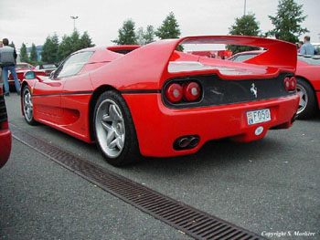 RE: Spoiler alert: PH Blog - Page 8 - General Gassing - PistonHeads - The image showcases a vibrant red Ferrari F40 with its back on a grate road on what appears to be a cloudy day. The F40 is parked in front of a grouping of people and other cars, suggesting a gathering or exhibition. This particular model of the Ferrari is well known for its aerodynamic design and modern styling. The clear focus on the Ferrari from this angle, looking from behind towards the front, underscores its prominence and aesthetic appeal. Its bright color stands out against the more subdued tones of the surrounding environment. Overall, the image captures a moment that exudes luxury, performance, and craftsmanship.