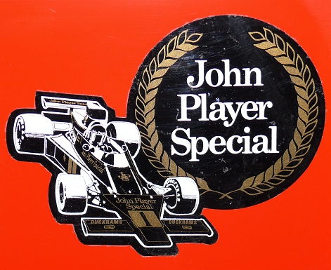 Show Us Your Stickers! - Page 1 - Formula 1 - PistonHeads - The image appears to be a graphic element commonly used to promote or brand John Player Special. It features a racing car within a circle, encased by a laurel wreath, a classic logo representing the award-winning race car team. The main text "JOHN PLAYER SPECIAL" is prominently displayed above the car. The logo is set against a red background, creating a striking contrast with the car's primarily black and white design.