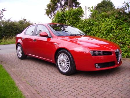 Driver Daily Pistonheads Diesel - The image shows a sleek, red sports car parked in a driveway. The vehicle is situated in front of a brick wall, with trees and shrubbery visible in the background. The car is not currently in use, as indicated by no visible lights or moving parts. Its design features modern lines and a polished exterior, suggesting it is well-maintained or recently cleaned. There are no visible texts or logos on the car, keeping the focus squarely on its aesthetics and the setting in which it is parked.