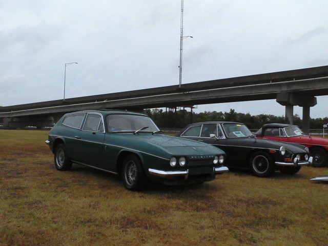 Car Show vs Hurricane Sandy - Page 1 - USA & Canada - PistonHeads - The image shows a grassy field under an overcast sky. Two antique cars are parked in the field, positioned adjacent to each other. Their colors are different: one is green, and the other is black. They are positioned near the right side of the image. Interestingly, there is a modern, red car parked on the left side of the image, contrasting in both its color and its modern design. The juxtaposition of the vintage cars with the modern one creates a unique blend of eras and styles.