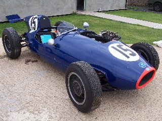 Gathering Essex Weekend Pistonheads Fairthorpe - The image showcases a vintage racing car, specifically from the team Kojima, boasting a vibrant blue and red color scheme. The car is adorned with the number 15, prominently displayed on the hood and the driver's side door. The setting is an outdoor environment, with the car stationary on a concrete surface, suggesting a quiet moment of display or perhaps repair from a previous race. The car's position and the surrounding environment imply it might be a part of a larger track or racing event.