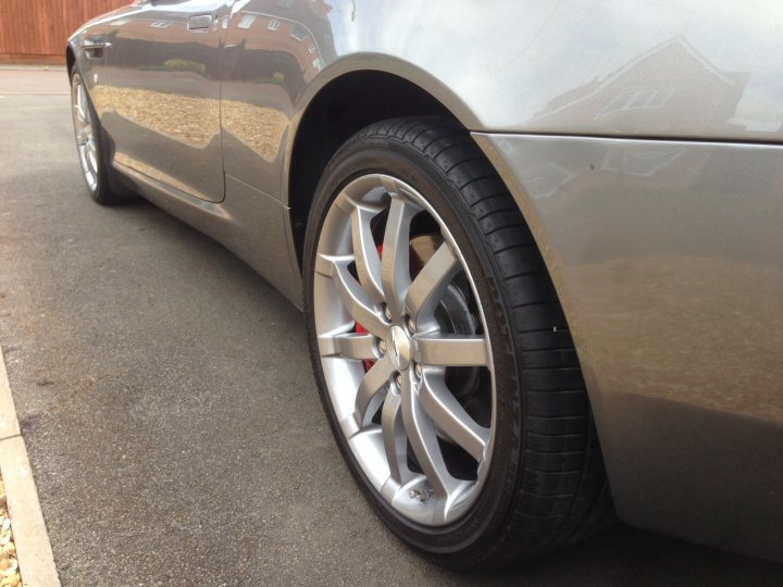 Alloy refurbishment - Page 1 - Northamptonshire - PistonHeads - The image features a close-up view of a silver car's front right tire. The tire is positioned at an angle and is firmly attached to the car. Reflections are visible on the tire's rim, indicating it might be a sunny day or there is a shiny surface nearby. The surrounding area appears to be a parking lot with no other vehicles or significant features in immediate sight. The focus of the image is clearly on the tire, perhaps highlighting the wheel or the condition of the tire.