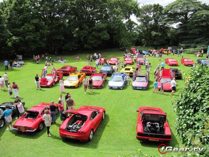 August Hedingham Castle Pistonheads - The image showcases a large, open field teeming with life and color. Dominating the scene is a grand gathering of cars, with models ranging from sedans to convertibles. These cars are parked in neat rows, their metallic bodies gleaming under the outdoor light. The field itself is lush and green, providing a vibrant backdrop to the assembly of vehicles. Mingling through this motoring spectacle are numerous people, their figures small against the grand scale of the gathering. The overall mood of the image is one of excitement and anticipation, hinting at an event of significance for the car enthusiasts visible in the scene.