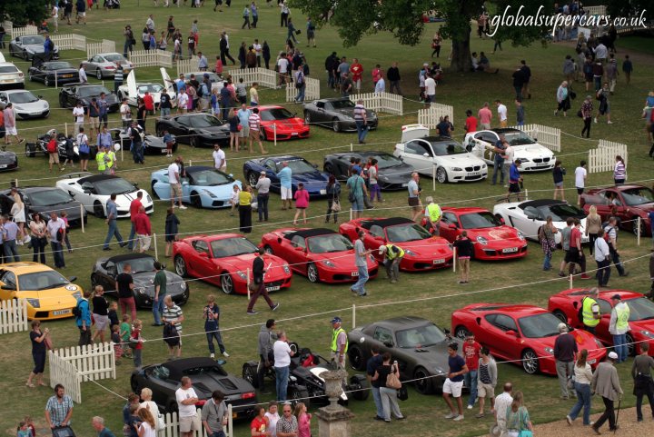 A group of people standing on top of a lush green field - Pistonheads - The image showcases a bustling car show on a grassy field. Numerous cars of various makes and models are parked in well-maintained rows, attracting a sizable crowd. People are milling about, inspecting the cars, and likely discussing their features. The background reveals a line of trees, adding a touch of nature to the event. On the right side of the image, there's a clear sky, suggesting a sunny day, which is ideal for outdoor events.