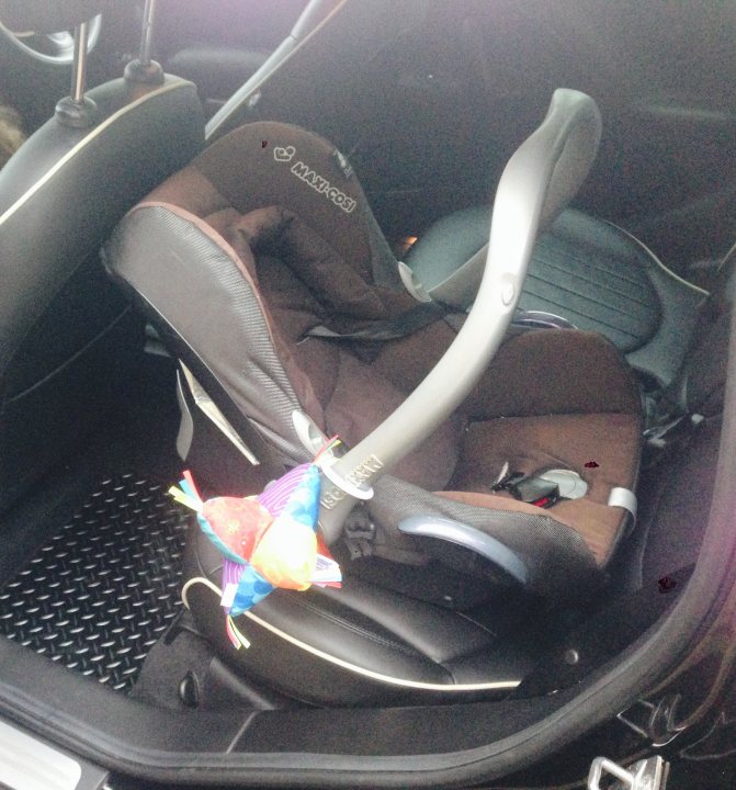 A bag of luggage sitting on top of a floor - Pistonheads - The image shows the inside of a car with a child car seat installed. The car seat is dark in color, and its canopy is raised. A colorful item, possibly a toy, is placed on the seat. It looks like a brightly colored owl or bird, with streamers on its head. The toy appears to be attached to the car seat latch, indicating it might be a keychain for keys or luggage, or possibly a security grip for the toy if it were part of a set.