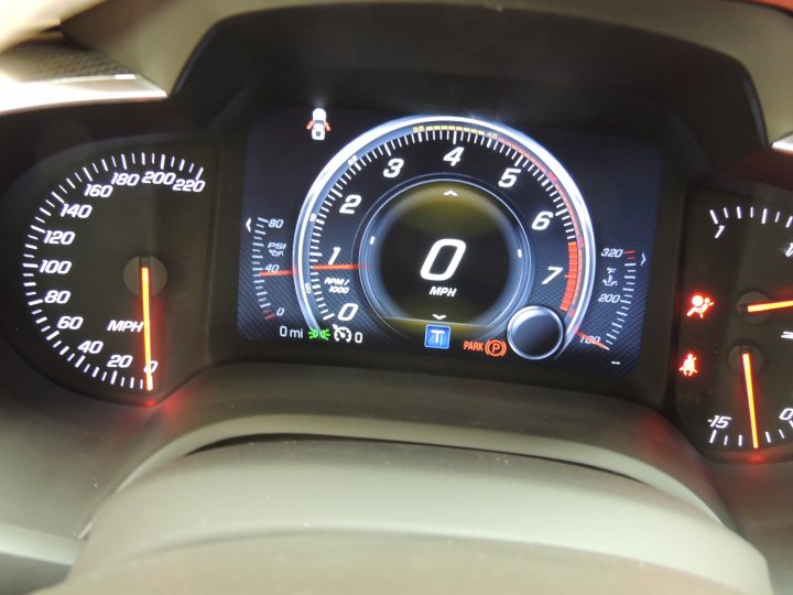 A close up of a car parked on a street - Pistonheads - The image captures the driver's side of a car, focusing on the instrument cluster. The digital display on the dashboard indicates a speedometer reading of 0 mph, suggesting the car is either stopped or that the image was taken in a static situation. The cluster is illuminated, with the dashboard and gauges ready for use. The interface is neatly laid out, with clear callouts and values displayed, reinforcing a modern, digital design of the dashboard.