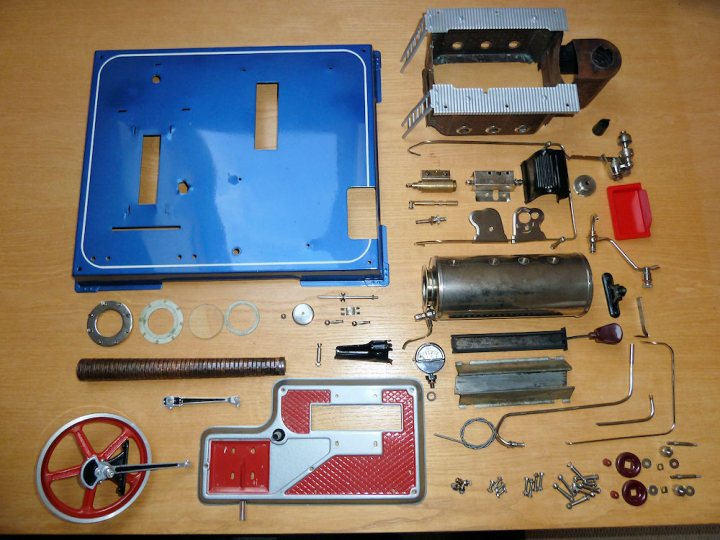 Model Steam Engine - Page 2 - Scale Models - PistonHeads - The image presents a collection of various mechanical and electrical parts laid out on a wooden table. The parts are diverse, including gears, wiring, and what appears to be a drill assembly. The arrangement suggests an organizing or refurbishing process, aiming to separate and possibly repair or reuse these components. The setting conveys a sense of "work in progress," with materials and hardware being sorted or prepared for a project.