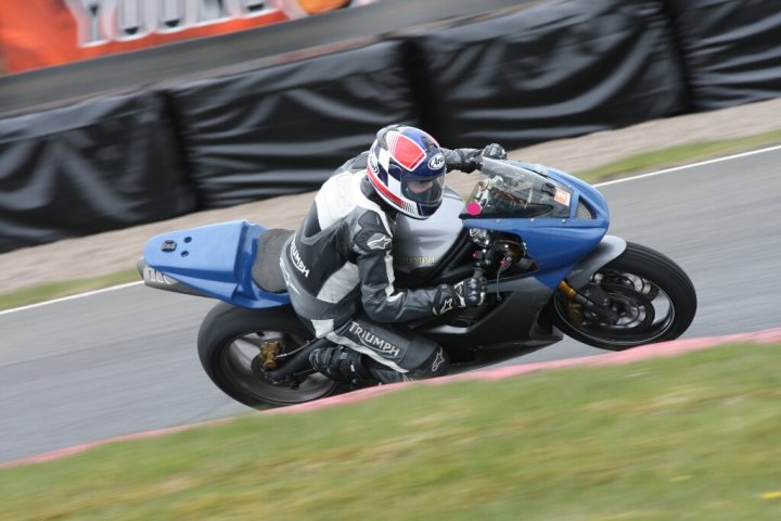 the bb trackday thread.   - Page 430 - Biker Banter - PistonHeads - The image captures a dynamic moment on a race track. A motorcycle rider, clad in protective gear, is sequentially airborne in three stages, creating a sense of motion and speed. The background is blurred, emphasizing the motion of the rider. The track itself is bordered by a fence, under what appears to be a blue sky. The focus is entirely on the motorcyclist, underscoring the intensity and thrill of the scene.