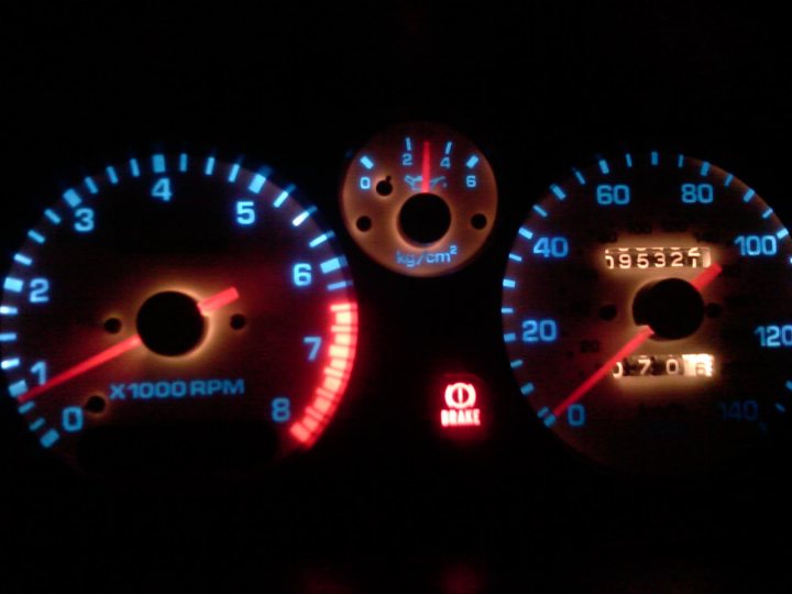 Pistonheads - This image captures the dashboard of a vehicle during a night drive. The focus is on the illuminated speedometer and odometer. The speedometer needle is hovering around the 60 mile per hour mark, indicating the vehicle is traveling at a relatively moderate speed. The odometer shows a reading of "59632", suggesting that the car has been driven for approximately 596,320 miles. On the right, the digital clock displays "12:00", which typically denotes midnight. The vehicle is designed such that the speedometer and its corresponding needle are located at the left side of the instrument cluster, while the odometer and clock are situated on the right.