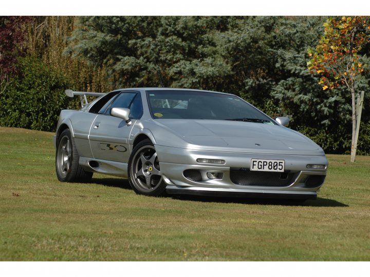 Sport 350 - any owners tempted to sell? - Page 1 - Esprit - PistonHeads - This image shows a silver convertible sports car parked on grass, which gives an impression of serenity. It stands out in the landscape, contrasting with the natural elements surrounding it. The car has a sleek and refined design, with stylish alloy wheels and tinted windows. A tree can be seen in the background, adding to the peaceful environment.