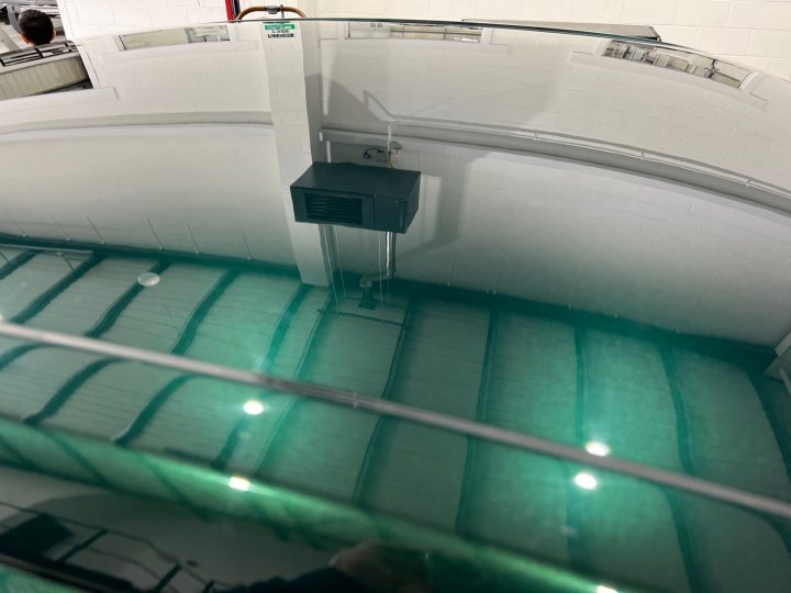 R33 GTR Restoration - Page 1 - Readers' Cars - PistonHeads UK - The image shows an interior view of a large rectangular pool filled with murky green water. The floor of the pool has several white tiles, and there appears to be some sort of equipment or mechanism at one end. The walls are tiled, and it looks like a space designed for swimming or diving activities. Above the pool, there's a structure that might be a diving board or platform, but its details aren't clear. There is no visible text or distinctive markings on the tiles or other surfaces in the pool. The focus of the image is primarily on the pool itself and the surrounding equipment.