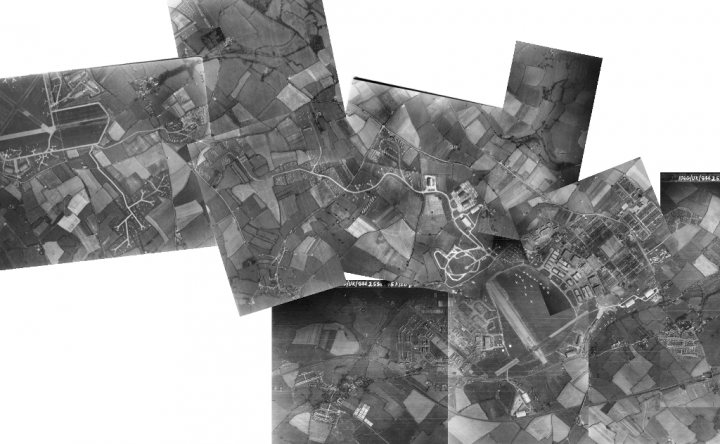 A black and white photo of a large building - Pistonheads - This image features various aerial maps, seemingly black and white, layered on top of each other. Each map shows a different level of detail, including roads, rivers, and towns. The maps have a vintage or historical appearance. Overlaid on the maps is modern, white, large text that clearly shows "BAYER 1878." The style of the photograph blends old and new cartography, creating a unique juxtaposition.