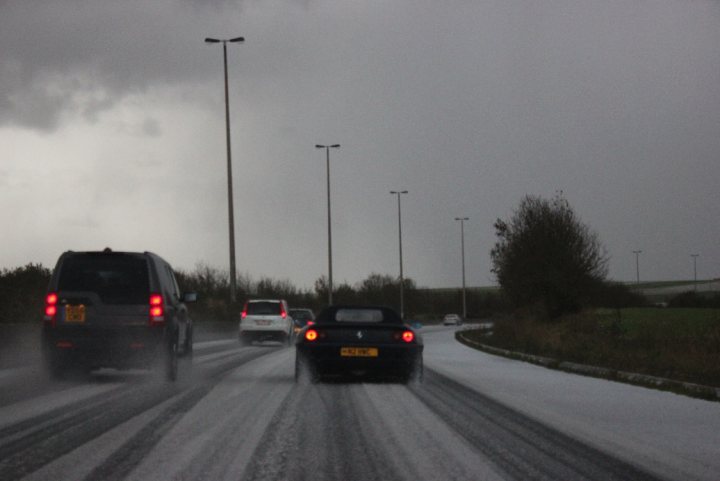 Most incongruous supercar photo thread - Page 1 - Supercar General - PistonHeads - This image captures a scene of a highway on a seemingly overcast or rainy day, as evidenced by the wet and snowy road. We see multiple vehicles, including a black car and a dark SUV, which are indicated by their respective position and size in the frame. The sky appears gloomy and dark, contributing to the somber atmosphere. The presence of several lamps suggests that this could be a roadside or a stretch of roadway. Overall, this image conveys a typical winter or post-rain day scenario on a multi-lane highway.