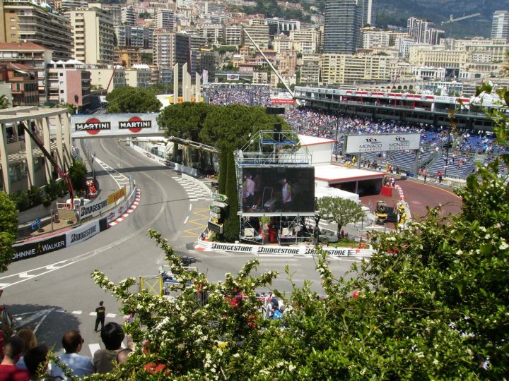 F1 In Monaco Cheapest way to see it ? - Page 1 - France - PistonHeads - The image presents a vibrant cityscape with aFocus sign, visible from a bird's-eye view. The city is bustling with life, and to the right of the image, a street sign is visible. The environment is lush with numerous trees and plants, providing a refreshing contrast to the urban setting. Furthermore, the sky above is a clear blue, dotted with fluffy white clouds, completing the picturesque view of the cityscape.