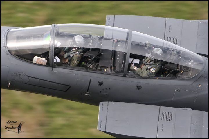 Mach Loop Typhoon ‘Incident’. - Page 4 - Boats, Planes & Trains - PistonHeads - The image captures an active scene inside the cockpit of a fighter jet. The jet is primarily composed of metallic gray, the color classic to the alliance. Guiding the operation are two pilots, their faces focused, oblivious to the surrounding world. The cockpit is a command center of precision and technology, encased in a canopy secured with straps. The jet is caught mid-flight, against the backdrop of a verdant landscape. The image seems to have been taken in broad daylight, with the jet's powerful structure standing in stark contrast to the tranquil greenery below.