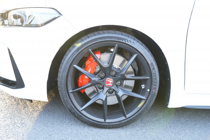 2023 Honda Type R - FL5 availability - Page 12 - Honda - PistonHeads UK - The image shows a car with a black and silver wheel. The wheel has a red caliper, which is unusual for most cars due to the color of the brakes. The vehicle appears to be stationary, possibly parked on the side of a road or in a parking lot. The car itself looks modern and sleek, with a white exterior that provides contrast with the black and silver wheel. The photo seems to have been taken during the day under clear weather conditions.