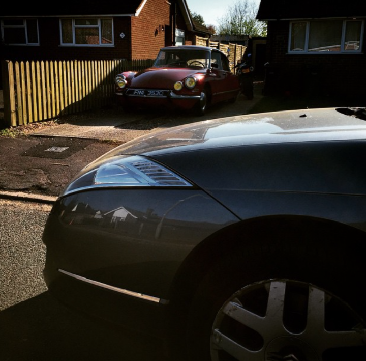 High risk, (potentially) high reward purchase - Citroen C6 - Page 3 - Readers' Cars - PistonHeads UK - The image captures a tranquil suburban scene. A classic red car, reminiscent of the 1960s, is parked on the left side of the street. It's next to a beige car and a gray car, both parked neatly along the curb. The street itself is lined with houses, their windows reflecting the clear sky above. A single tree can be seen in the background, adding a touch of nature to this residential area. The overall atmosphere of the image is calm and peaceful, as if time has paused in this quiet neighborhood.