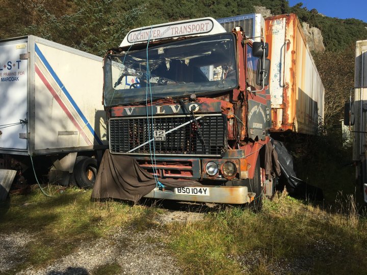 Classics left to die/rotting pics - Vol 2 - Page 219 - Classic Cars and Yesterday's Heroes - PistonHeads - The image shows an old, rusted truck parked in a lot with other vehicles. The truck's paint is fading, and it appears to be of a type commonly used for hauling cargo or trailers. The surrounding environment includes grass, some vegetation, and another vehicle in the background that looks like a trailer. There are no visible people in the scene, which gives it a somewhat abandoned feel.