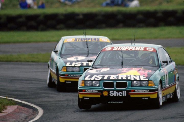 RE: The best BTCC car ever: PH Blog - Page 4 - General Gassing - PistonHeads - The image captures an exciting moment in a car race, with two vehicles from the Listerine team, numbered 9 and 18, charging ahead on an asphalt track. The car marked "9" is slightly behind the "18", both separated by a small distance. Above them, the sky is visible, meeting the track at the horizon. The environment suggests a competitive event, with fellow racers visible in the background. The vibrant green and yellow of the cars contrast sharply with the gray of the track, emphasizing the speed and intensity of the race.