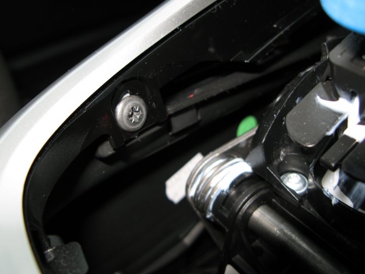 Pistonheads - The image is a close-up of the underside of a car's sporty, black headlight. A small bolt and a plastic cap can be seen, and one side of the car's black trim is clearly visible. The inside of the car's hood can be seen along the edge of the image, which exposes metallic components and cables. The focus is on the edges of the headlight, indicating attention to detail or the optical impact of these parts.