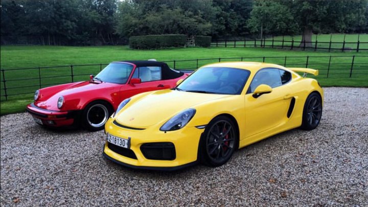 GT4 colours  - Page 72 - Boxster/Cayman - PistonHeads - This image shows a gravel surface with two convertible sports cars parked on it. On the left is a vibrant red car, while the car on the right is a vivid yellow. The red car has the top down, revealing its convertible design, whereas the yellow car appears to have the top up. Both cars have a sleek, low-profile design, typical of sports cars. The background is softly blurred, suggesting a focus on the cars, and hints of trees and green spaces can be seen, indicating that the location might be in a rural or forested area.