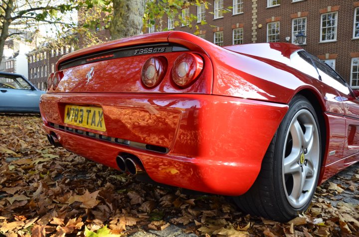 Classics in Queen Square - Page 7 - South West - PistonHeads - The image showcases a sleek red sports car parked on a street adjacent to a brick building. Its glossy finish reflects the surrounding architecture and greenery. The sports car's license plate reads "WR4 TAX." In the background, a tree with autumn foliage is visible, adding a touch of seasonal change to the urban setting. Another car is parked in the distance, indicating the car is not alone. The overall scene is a blend of urban life and nature.